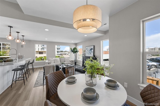 dining area featuring baseboards, visible vents, a healthy amount of sunlight, and light wood-type flooring