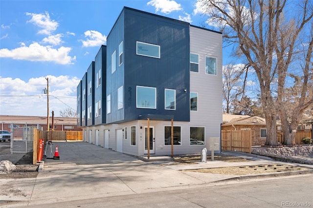 modern home featuring concrete driveway, fence, and a garage