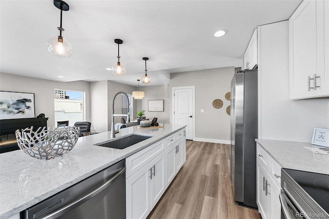 kitchen with light wood-type flooring, white cabinets, light stone counters, a sink, and stainless steel appliances