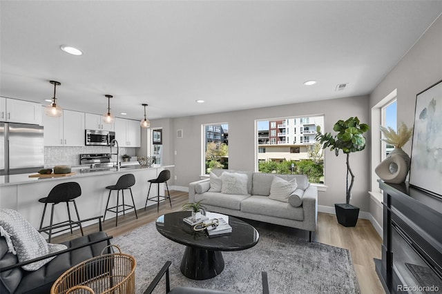 living room featuring recessed lighting, baseboards, light wood-type flooring, and visible vents