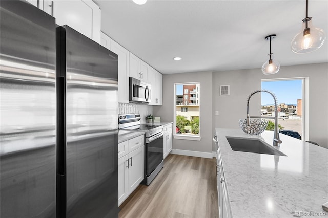 2140 S Ash St Unit 101, Denver, CO 80222 - kitchen with appliances with stainless steel finishes, a sink, white cabinets, light wood-style floors, and baseboards