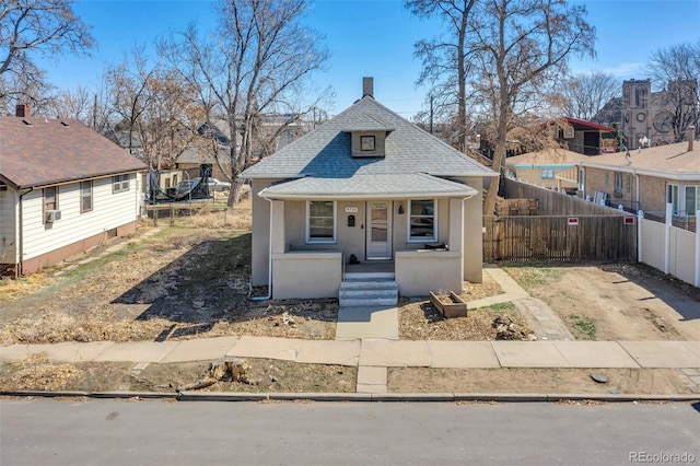 bungalow with a shingled roof, fence, a residential view, stucco siding, and covered porch