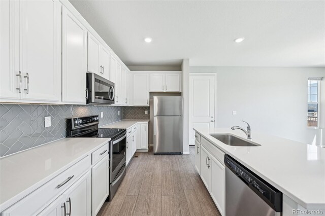kitchen featuring a sink, white cabinets, light countertops, appliances with stainless steel finishes, and backsplash