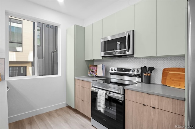 kitchen with appliances with stainless steel finishes, backsplash, light hardwood / wood-style flooring, and light brown cabinets