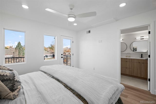 bedroom with access to outside, ensuite bathroom, sink, ceiling fan, and light hardwood / wood-style floors