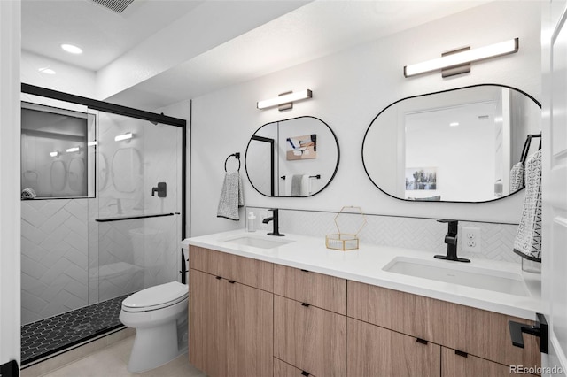 bathroom featuring vanity, toilet, a shower with shower door, and tasteful backsplash