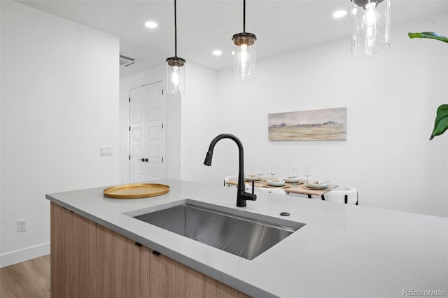 kitchen featuring pendant lighting, light hardwood / wood-style floors, and sink