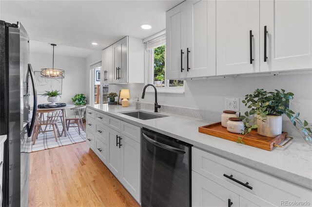 4650 S Idalia St, Aurora, CO 80015 - kitchen featuring stainless steel appliances, a sink, white cabinetry, a chandelier, and light wood-style flooring