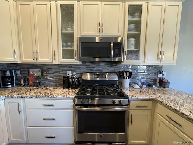 kitchen with light stone counters, appliances with stainless steel finishes, and decorative backsplash