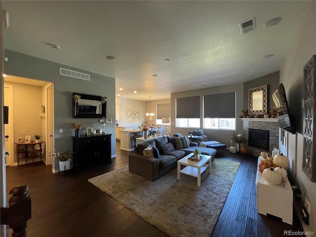 living room featuring dark wood-type flooring and a stone fireplace