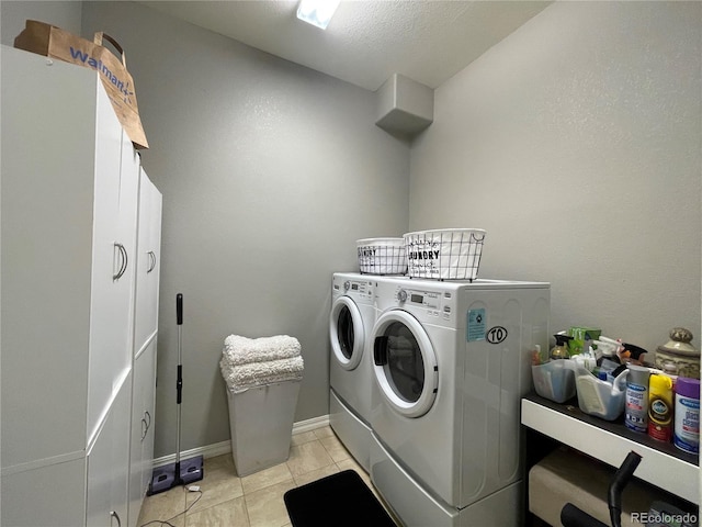 laundry area with a textured ceiling, light tile patterned flooring, washing machine and dryer, and cabinets