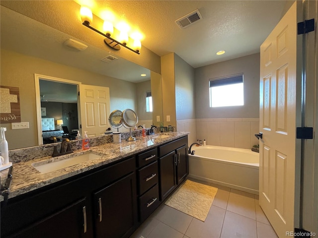 bathroom with a bathtub, a textured ceiling, tile patterned flooring, and vanity