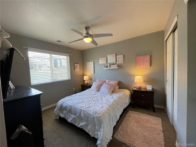 bedroom with dark colored carpet, a closet, a textured ceiling, and ceiling fan