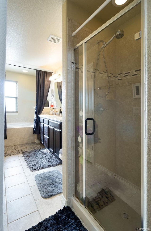 bathroom with plus walk in shower, a textured ceiling, vanity, and tile patterned floors