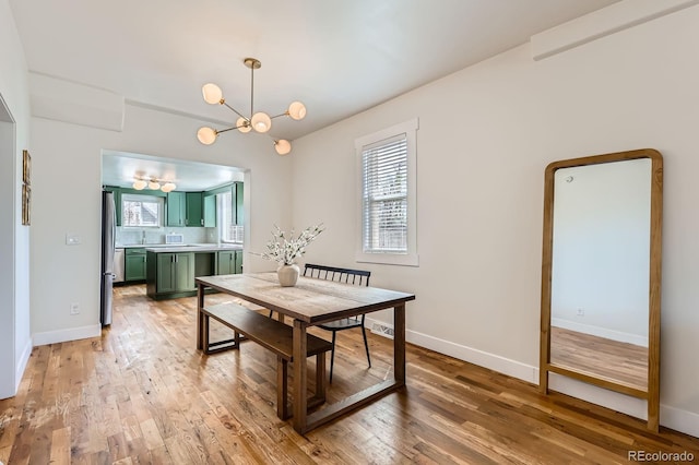 dining room featuring baseboards, an inviting chandelier, and light wood-style flooring