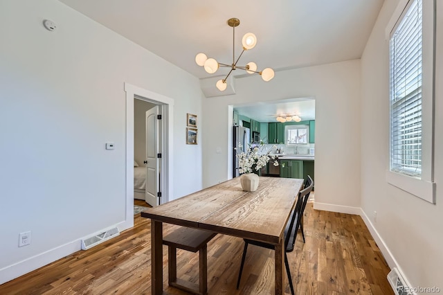 dining room with visible vents, baseboards, wood finished floors, and an inviting chandelier