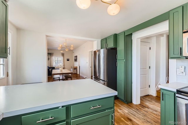 kitchen with a notable chandelier, green cabinetry, appliances with stainless steel finishes, and light wood-style flooring