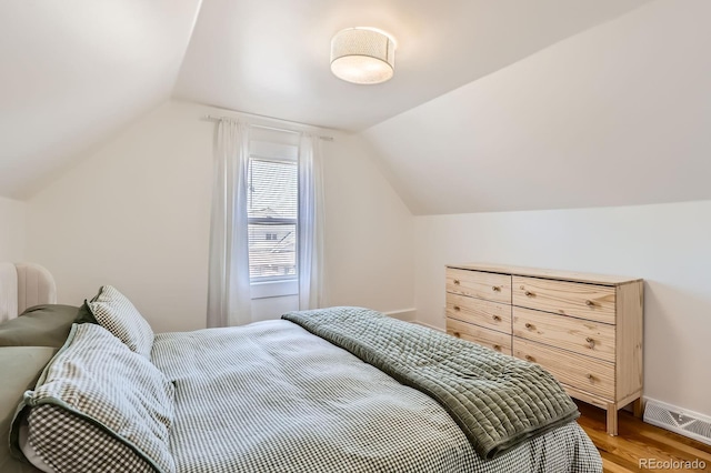 bedroom featuring baseboards, visible vents, light wood finished floors, and lofted ceiling