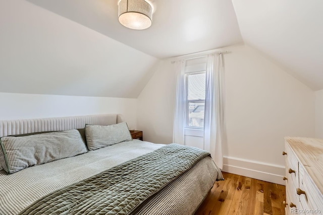 bedroom featuring baseboards, vaulted ceiling, and wood finished floors
