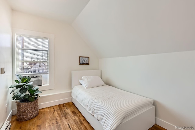bedroom featuring wood finished floors, cooling unit, baseboard heating, and vaulted ceiling
