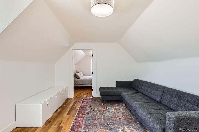 living area featuring baseboards, vaulted ceiling, and light wood-type flooring