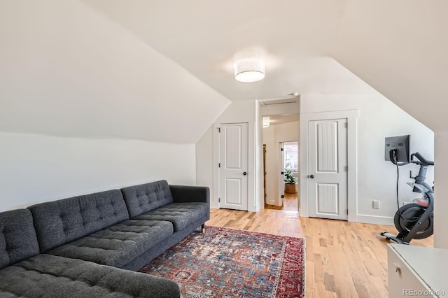 living area with baseboards, vaulted ceiling, and light wood finished floors