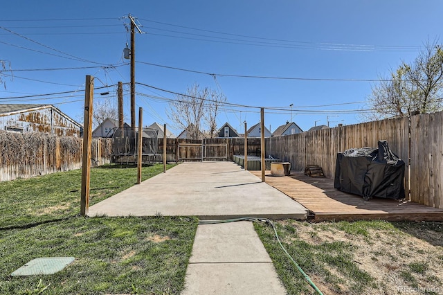 view of yard featuring a fenced backyard, a trampoline, a deck, and a patio