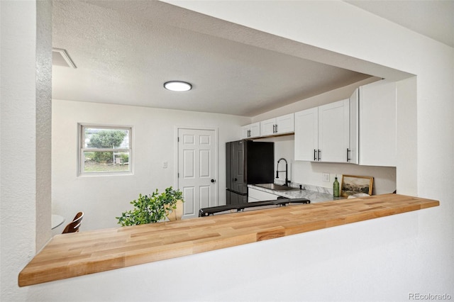 1330 Oak Pl, Thornton, CO 80229 - kitchen featuring butcher block counters, freestanding refrigerator, a sink, a peninsula, and white cabinetry