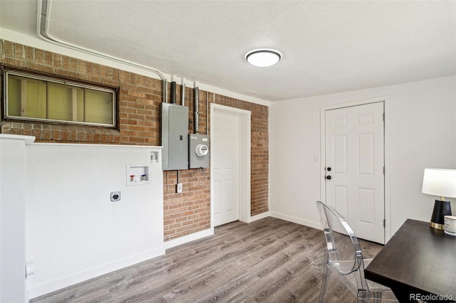 1330 Oak Pl, Thornton, CO 80229 - unfurnished office with electric panel, brick wall, wood finished floors, baseboards, and a textured ceiling