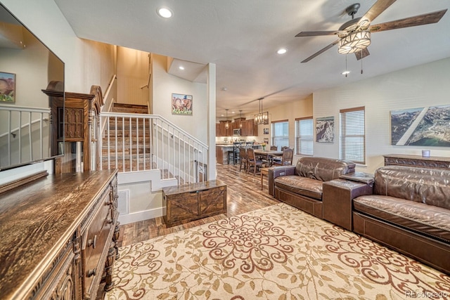 living room with ceiling fan with notable chandelier and light hardwood / wood-style flooring