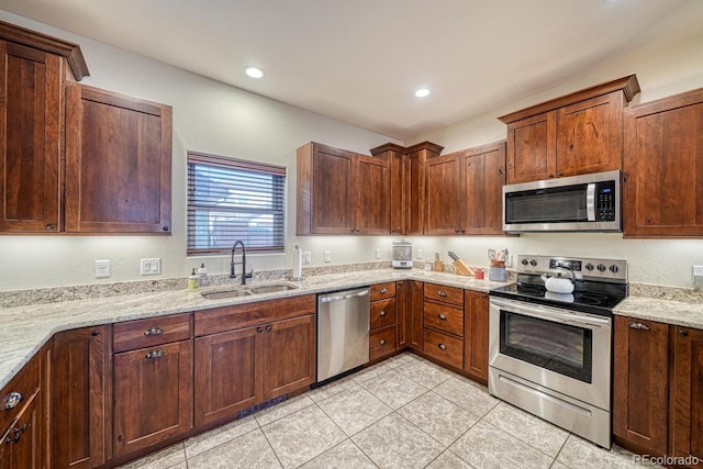 kitchen with sink, light tile patterned floors, stainless steel appliances, and light stone countertops