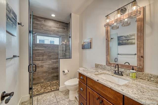 bathroom with a shower with door, vanity, tile patterned flooring, and toilet