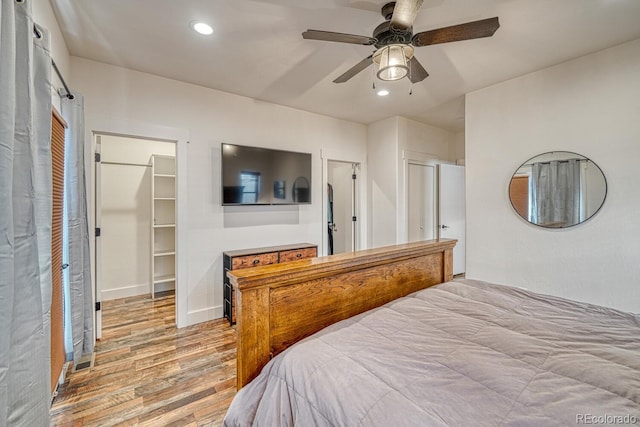 bedroom with ceiling fan, a spacious closet, a closet, and light wood-type flooring