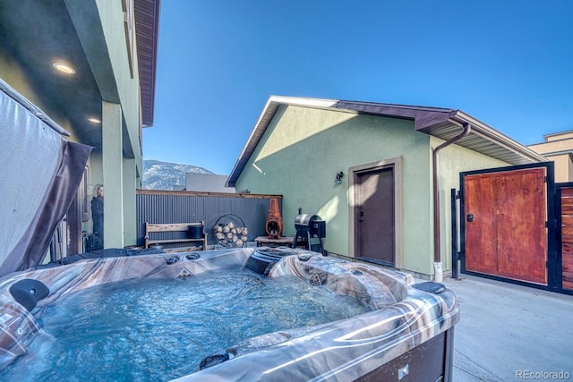 exterior space with a grill, a hot tub, and a mountain view