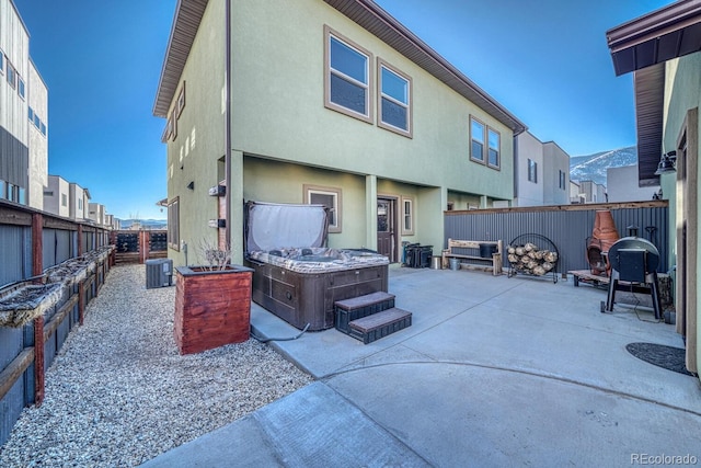 rear view of house featuring a hot tub, a patio, and central air condition unit