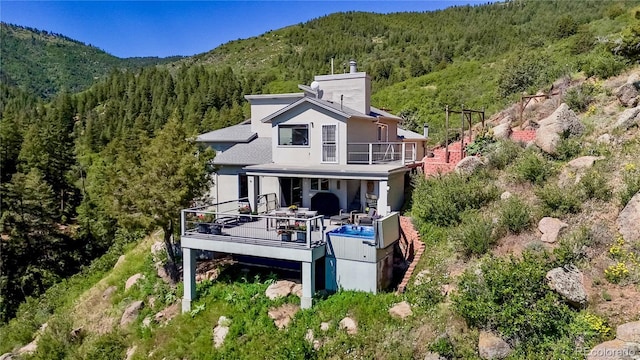 2602 Hidden Valley Rd, Sedalia, CO 80135 - rear view of property featuring a forest view, a chimney, a balcony, a mountain view, and stucco siding