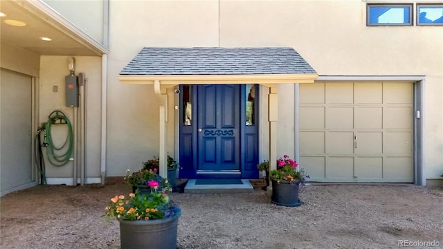 2602 Hidden Valley Rd, Sedalia, CO 80135 - view of exterior entry featuring a shingled roof, stucco siding, and a garage