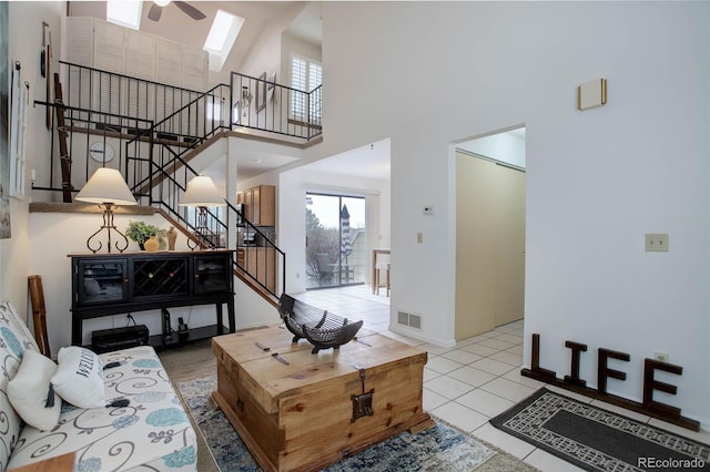 living room with ceiling fan, a towering ceiling, and light tile patterned flooring