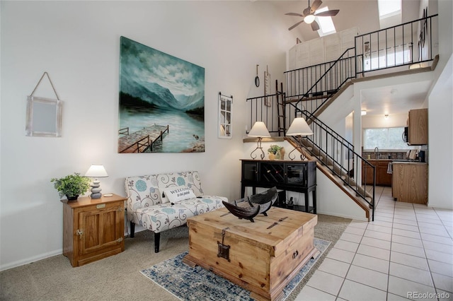 tiled living room featuring ceiling fan, a towering ceiling, and sink