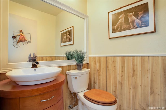 bathroom featuring vanity, toilet, and wood walls