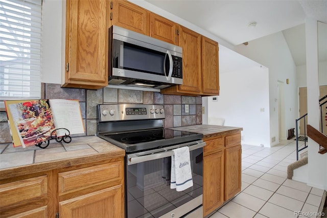 kitchen featuring backsplash, tile counters, light tile patterned floors, and stainless steel appliances