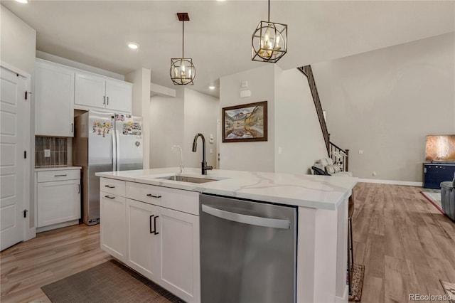 9836 Banner Peak St, Littleton, CO 80125 - kitchen featuring appliances with stainless steel finishes, open floor plan, light wood-style flooring, a sink, and light stone counters