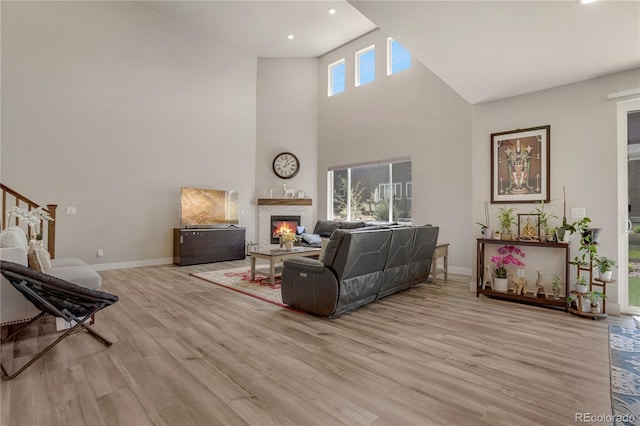 9836 Banner Peak St, Littleton, CO 80125 - living room featuring a glass covered fireplace, light wood-type flooring, baseboards, recessed lighting, and a high ceiling