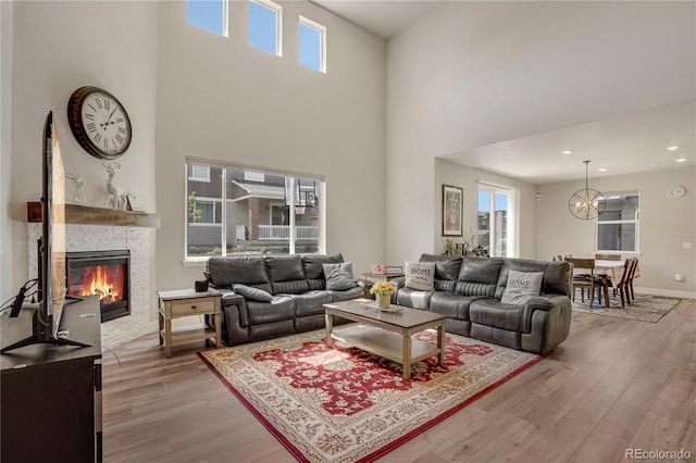 9836 Banner Peak St, Littleton, CO 80125 - living area with light wood-type flooring, a chandelier, a high ceiling, and a glass covered fireplace