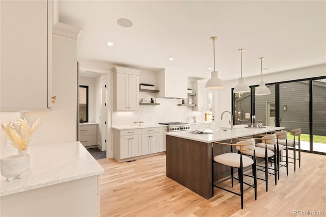 2610 N Monroe St, Denver, CO 80205 - kitchen with open shelves, a breakfast bar area, white cabinetry, light wood-style flooring, and recessed lighting