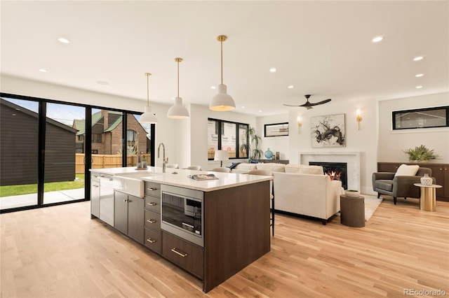 2610 N Monroe St, Denver, CO 80205 - kitchen featuring stainless steel microwave, a sink, light wood finished floors, a fireplace, and recessed lighting
