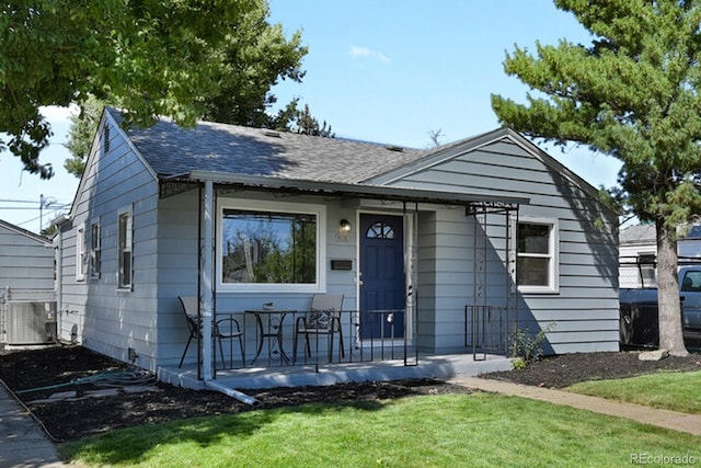 view of front facade with central air condition unit, a shingled roof, and a front yard