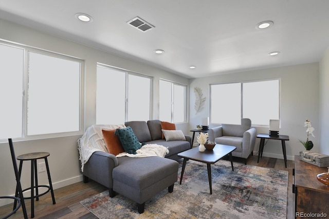 living room featuring baseboards, visible vents, wood finished floors, and recessed lighting