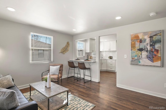 living room with baseboards, dark wood finished floors, and recessed lighting