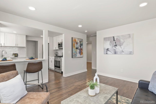 living room featuring recessed lighting, dark wood-style flooring, and baseboards